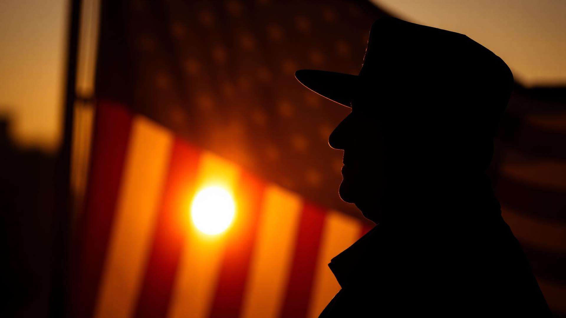 Veteran silhouette at sunrise with American flag
